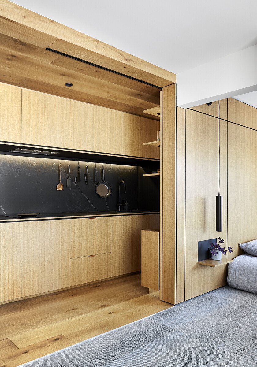 A fold-down dining table slides out from a hidden cavity, proving smart furniture can completely change how a small apartment functions.