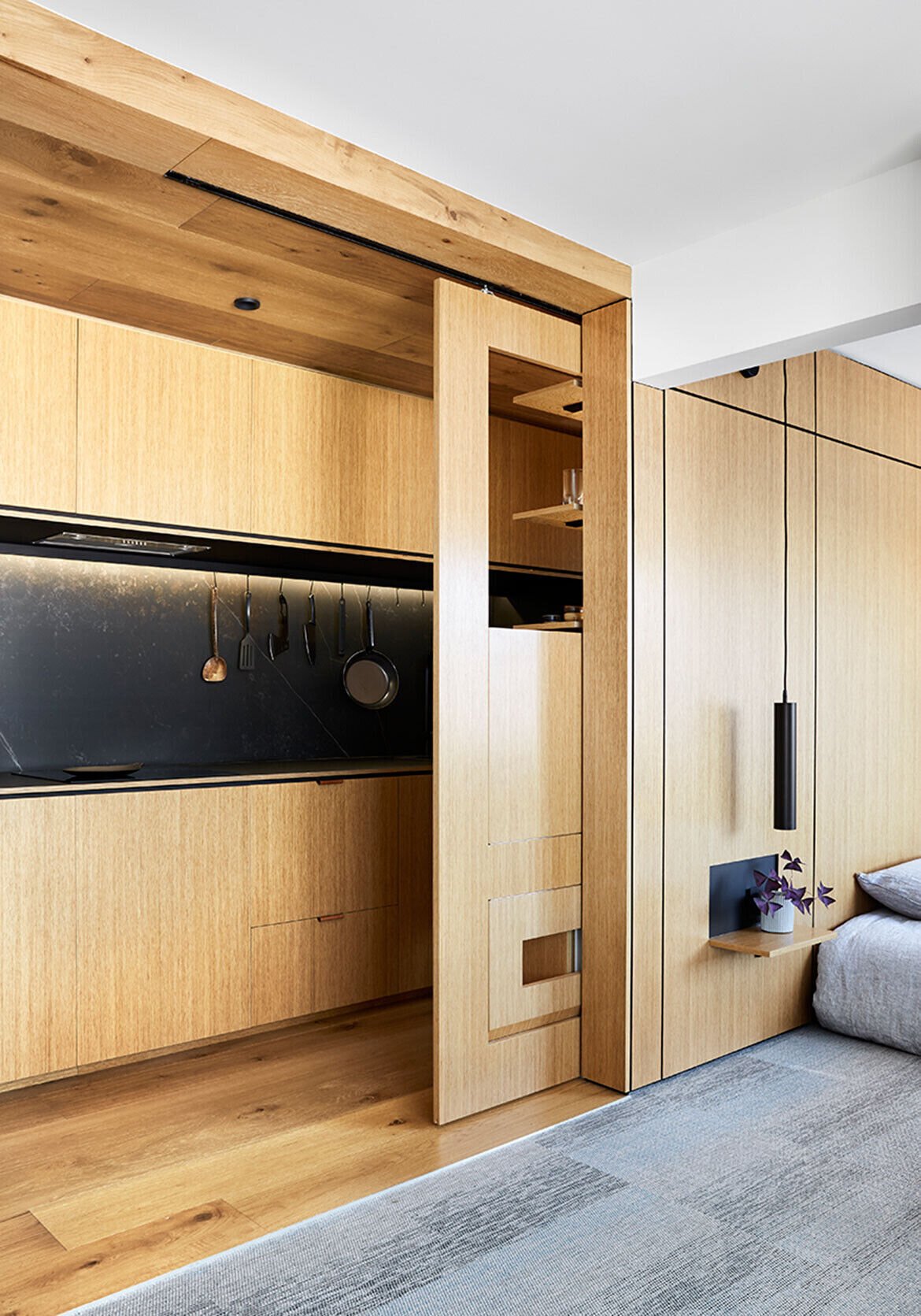 A fold-down dining table slides out from a hidden cavity, proving smart furniture can completely change how a small apartment functions.