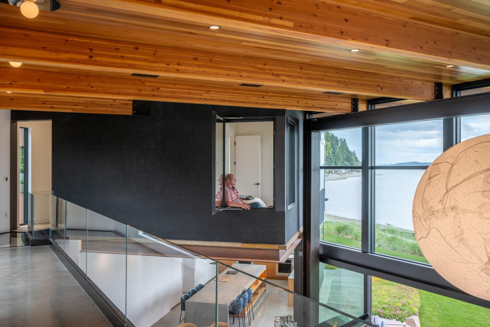 Bedrooms in a modern house have windows that look out to the water.
