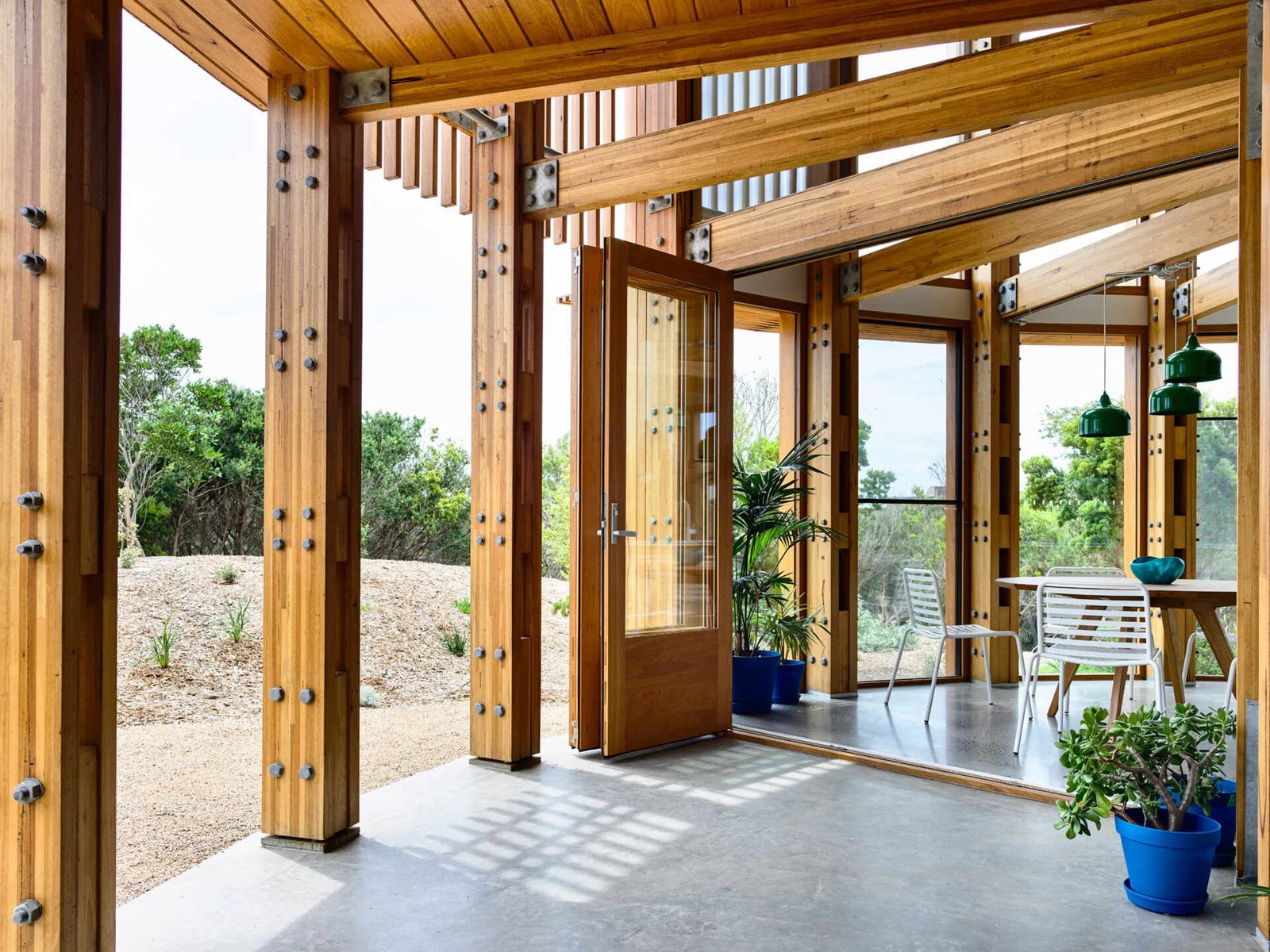 Open plan kitchen, dining and living areas inside a compact circular beach house designed for shared living.