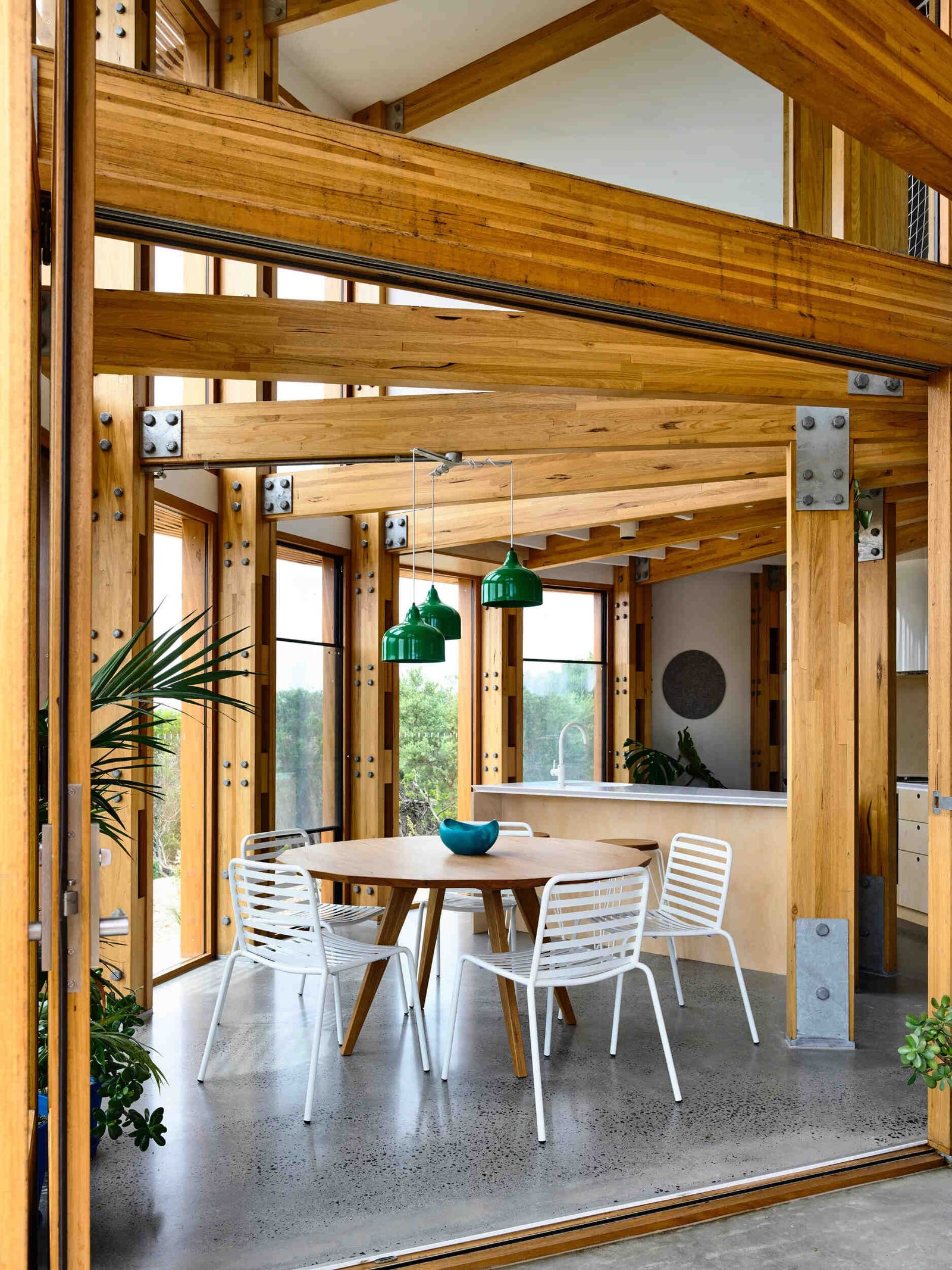 Open plan kitchen, dining and living areas inside a compact circular beach house designed for shared living.