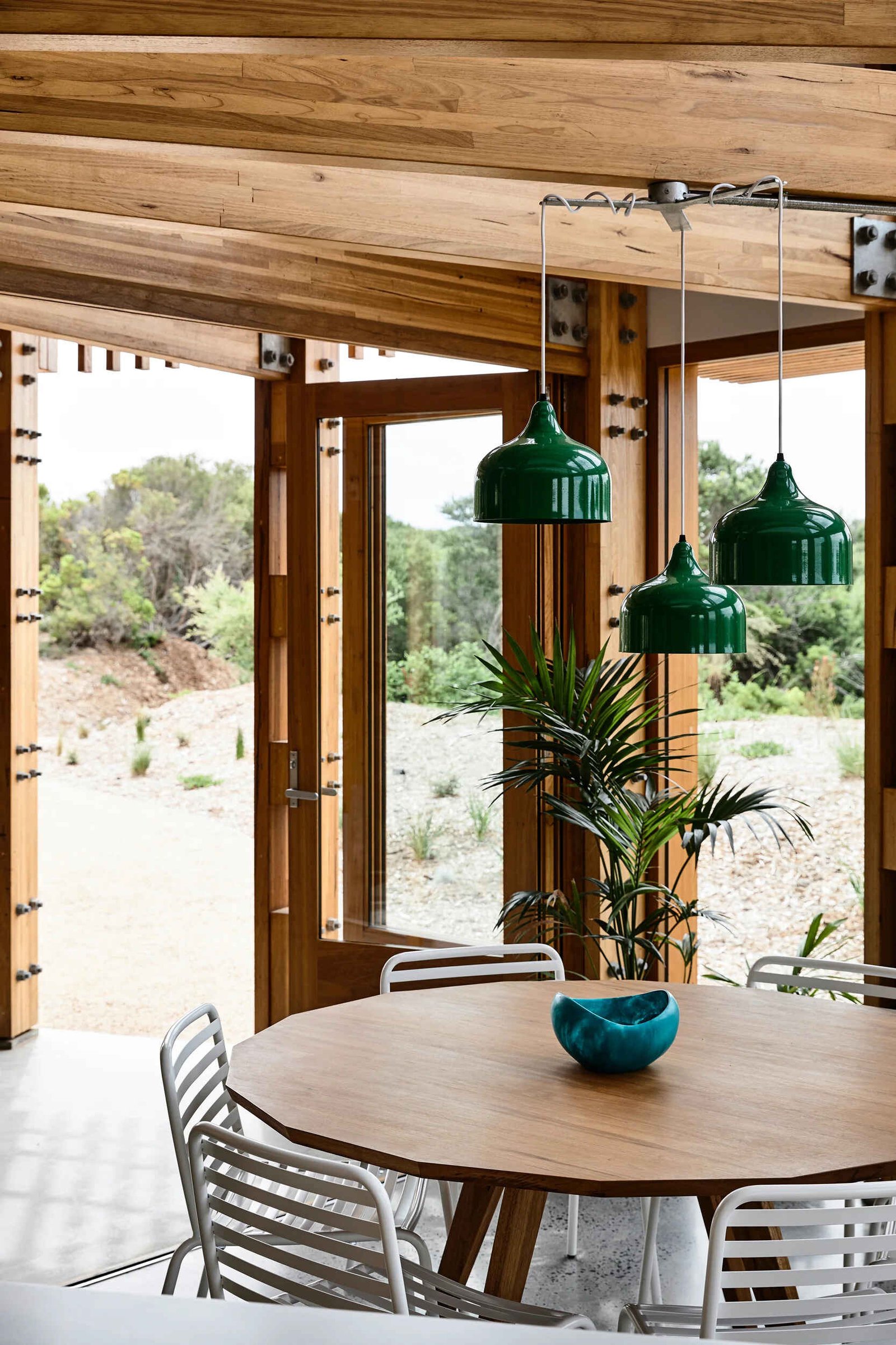 Open plan kitchen, dining and living areas inside a compact circular beach house designed for shared living.