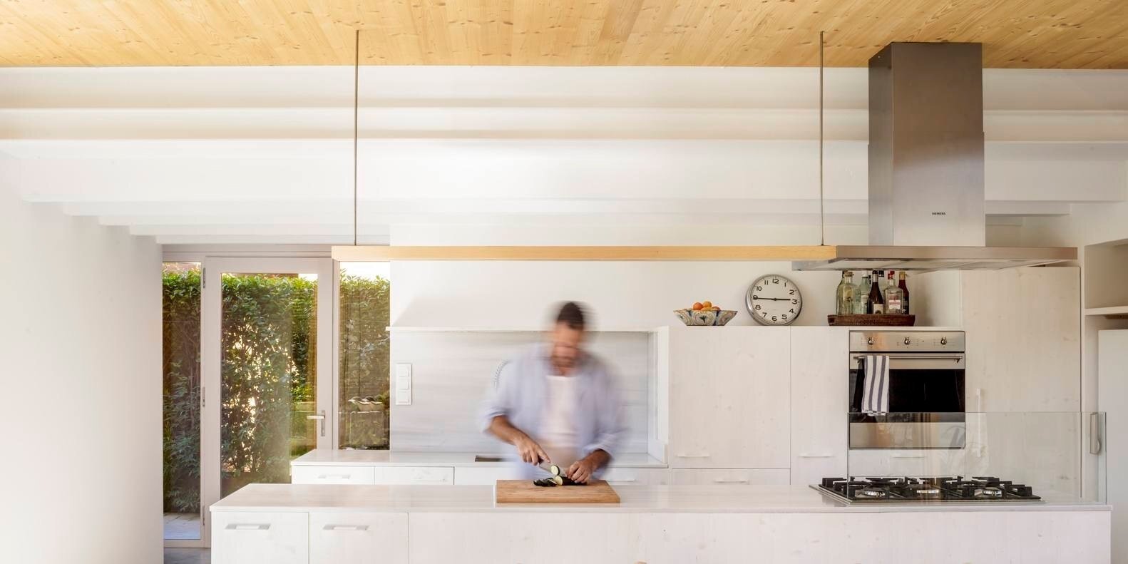 A long kitchen island anchors the entertaining space, designed for daily meals and gatherings while staying connected to the garden.