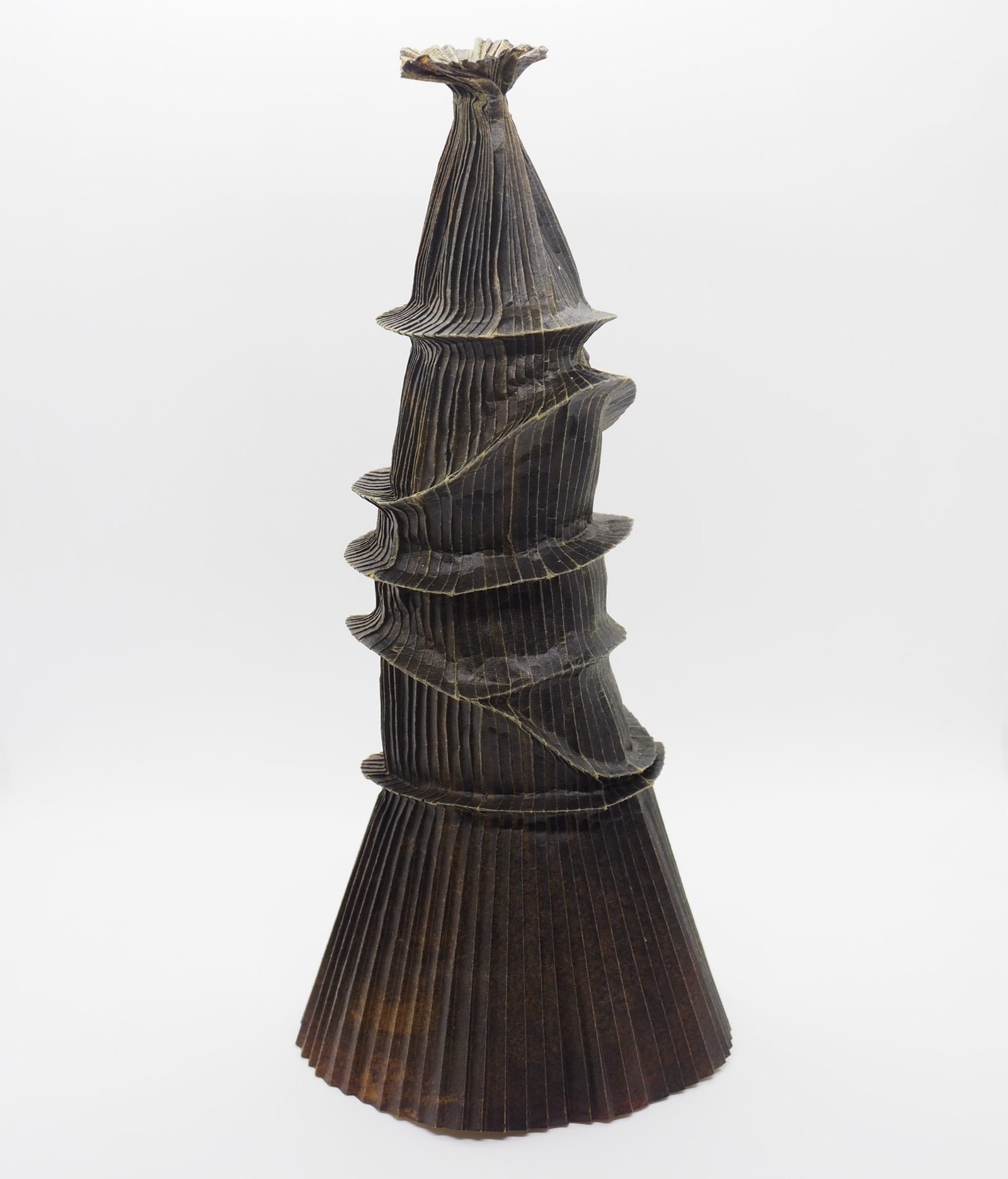 An origami paper vase with a wide base and narrow top, with uneven rim details around the body