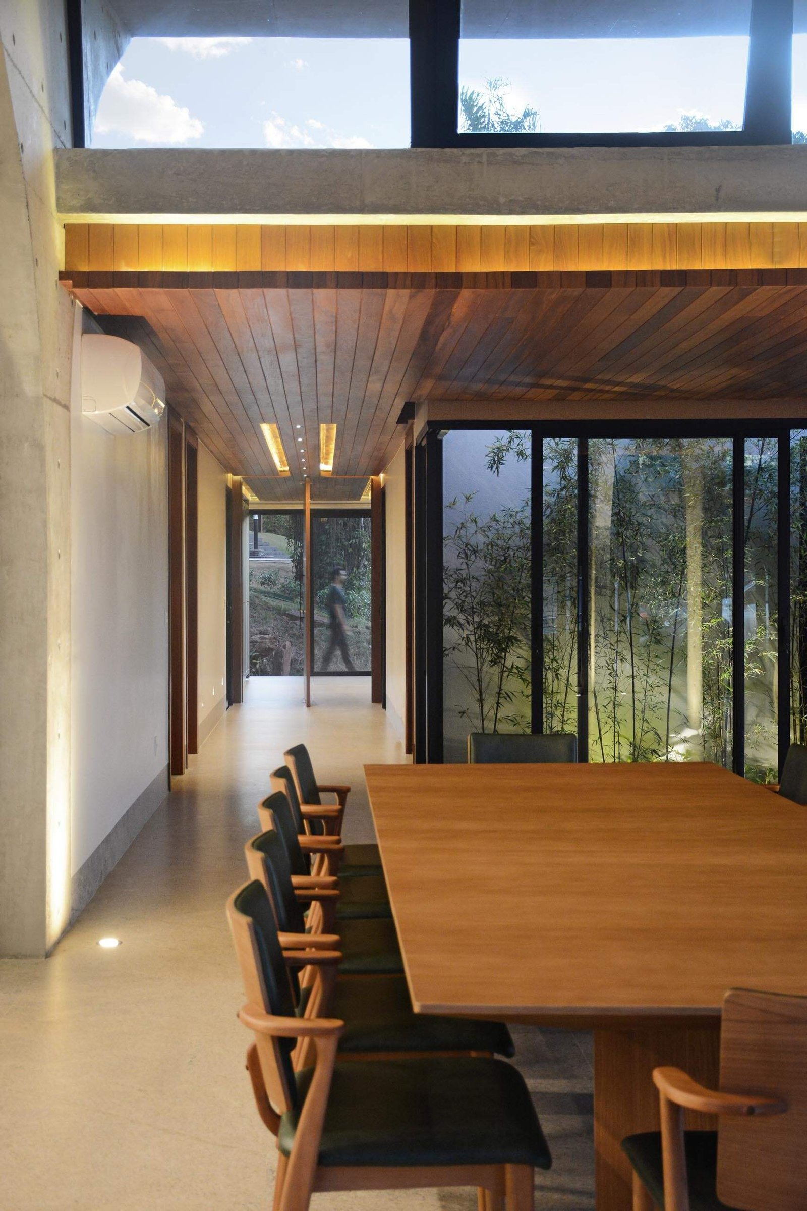 A pivoting front door and warm wood ceiling welcome visitors into Casa Joy, where exposed concrete arches create a bold architectural statement at the entry.