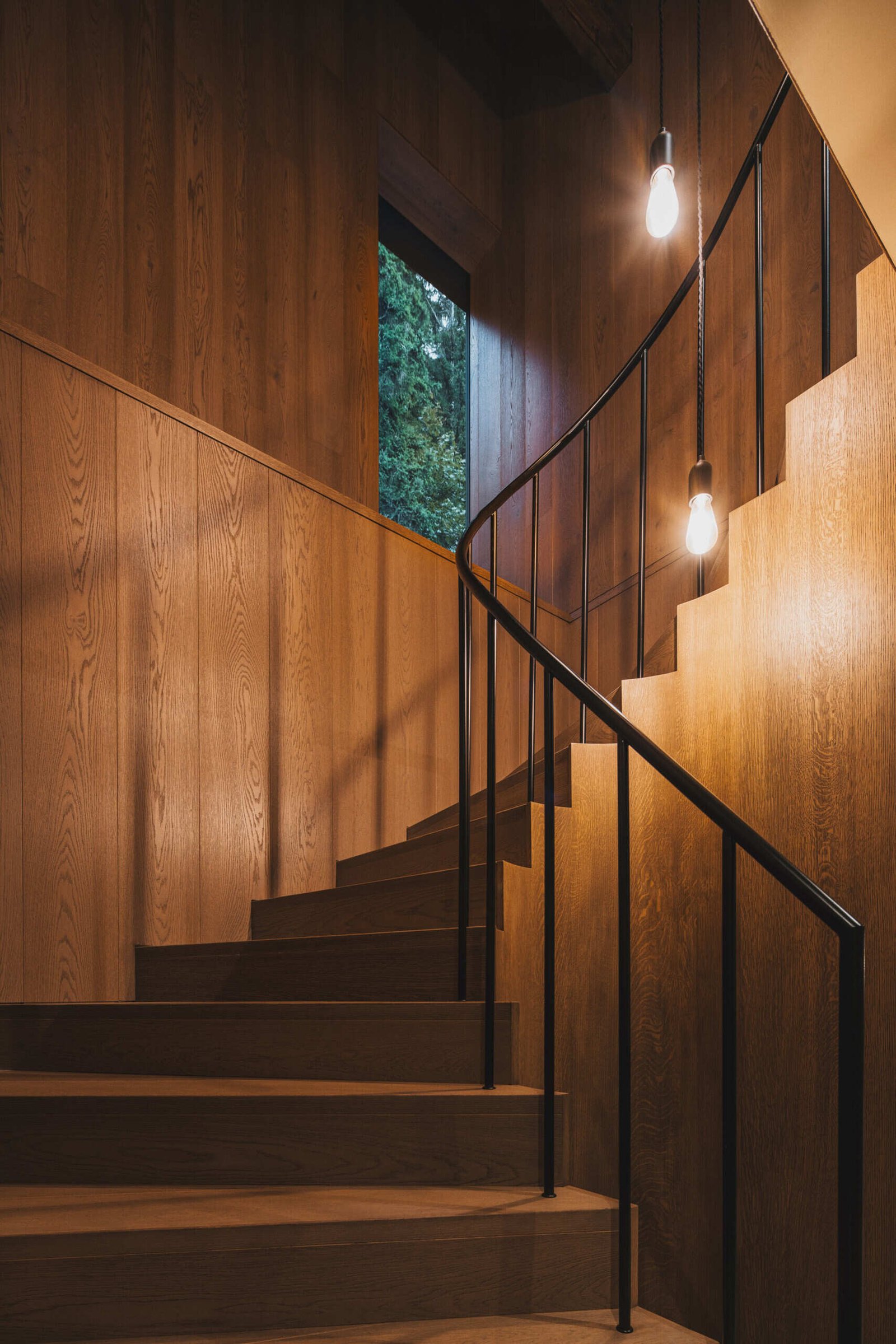 The wood staircase with black metal railing links the ground floor to the attic without disrupting the traditional layout. Its insertion respects the surviving structure while providing clear access to upper-level rooms.