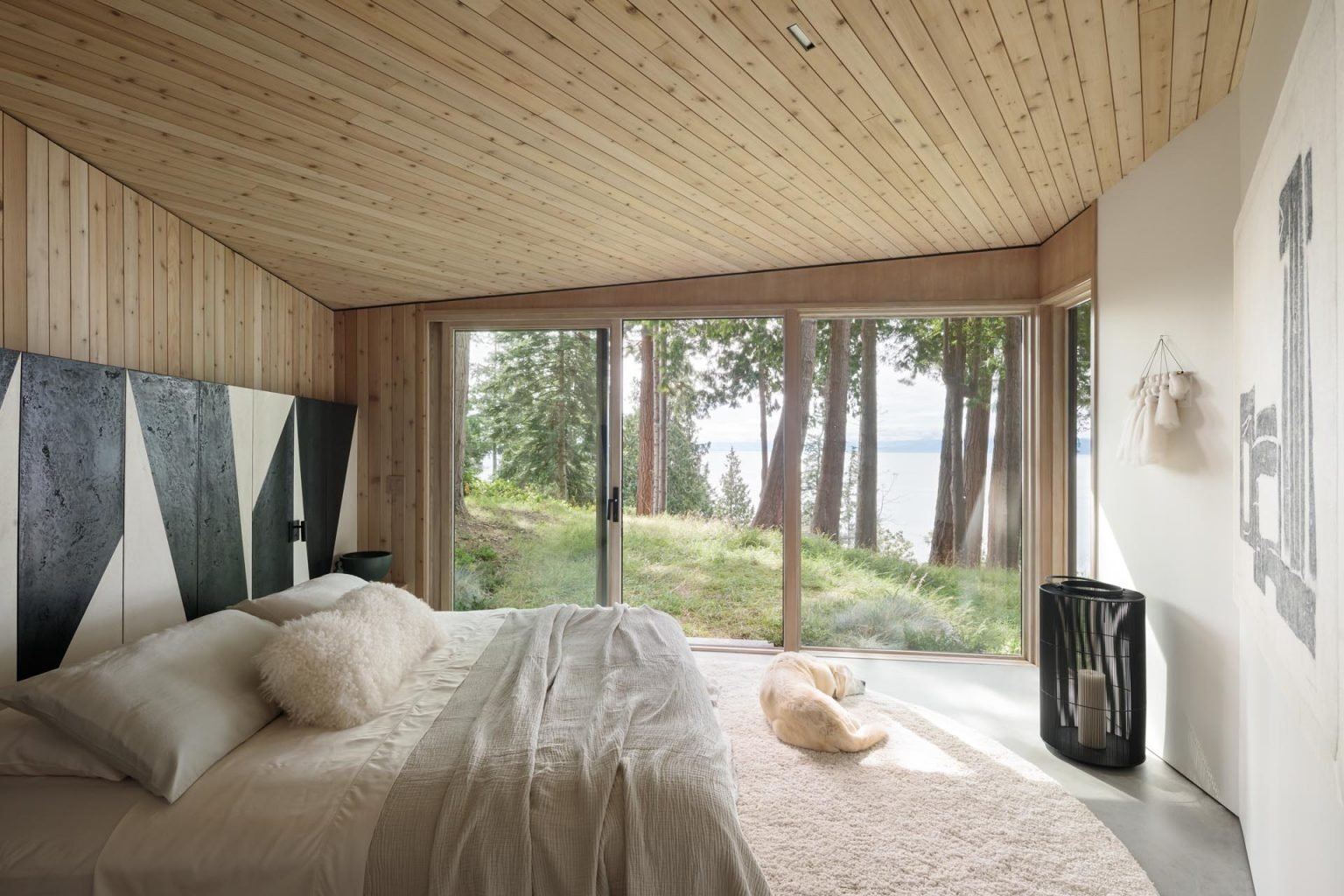 A bright bedroom with a full wall of windows and a bold black and white accent wall that adds a modern edge.