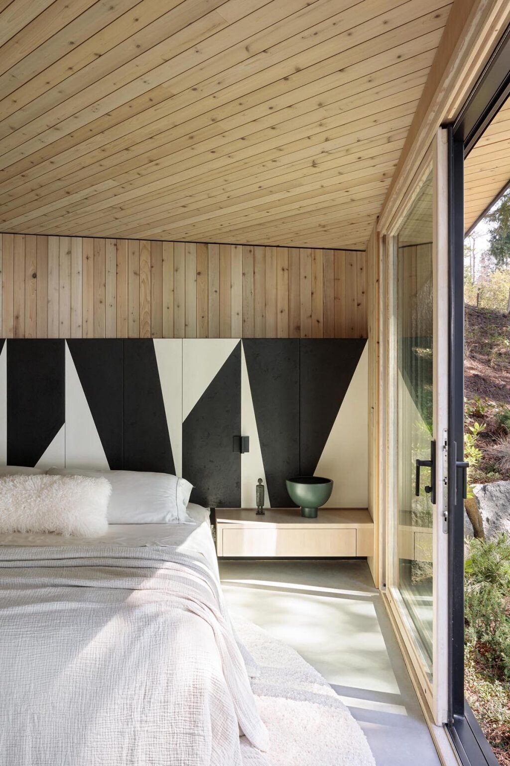 A bright bedroom with a full wall of windows and a bold black and white accent wall that adds a modern edge.