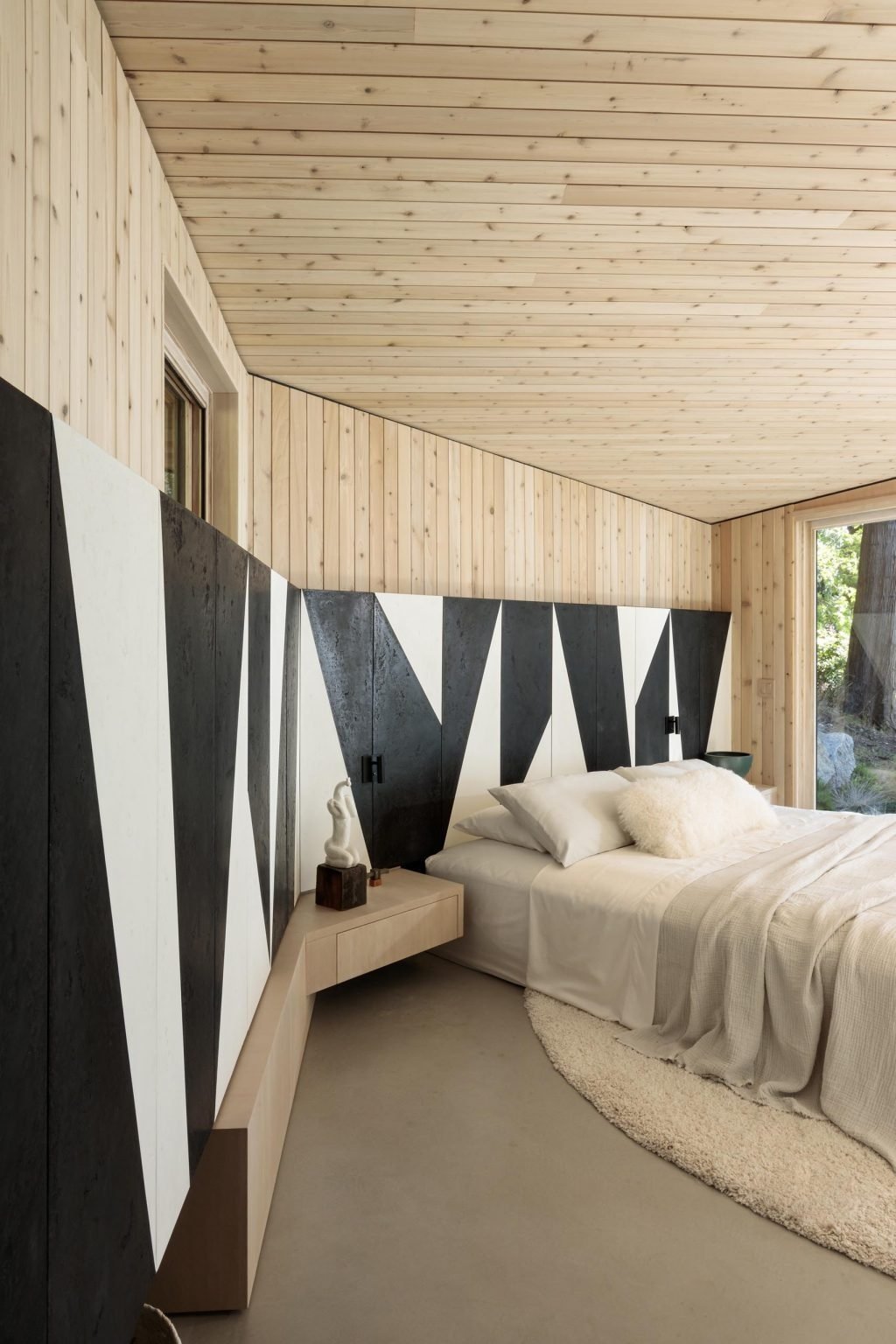 A bright bedroom with a full wall of windows and a bold black and white accent wall that adds a modern edge.