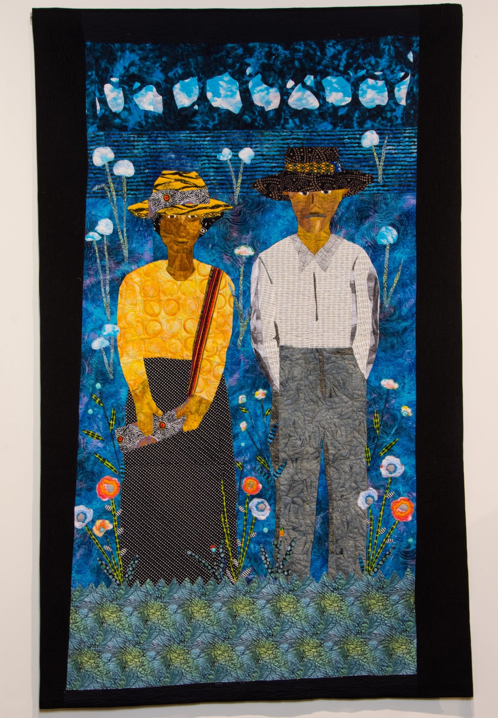 a portrait quilt of two Black figures against a blue background