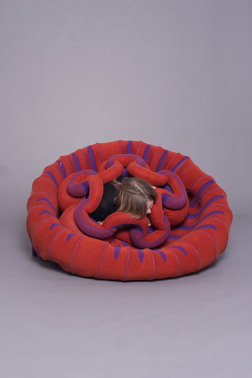 A user interacting with a flexible knitted textile piece by sitting and stretching it