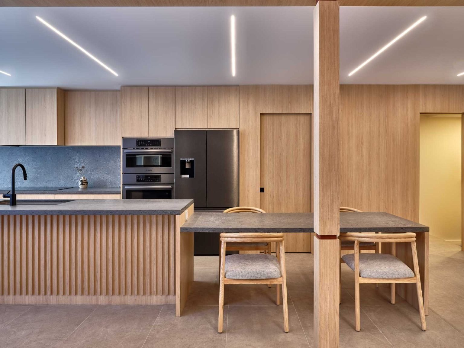 Modern kitchen with flat-panel oak cabinets, a central island, and integrated pocket doors