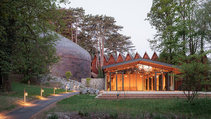 Exterior shot of the pre-patinated copper tile cladding of La Source Vive nestled into the green forest landscape
