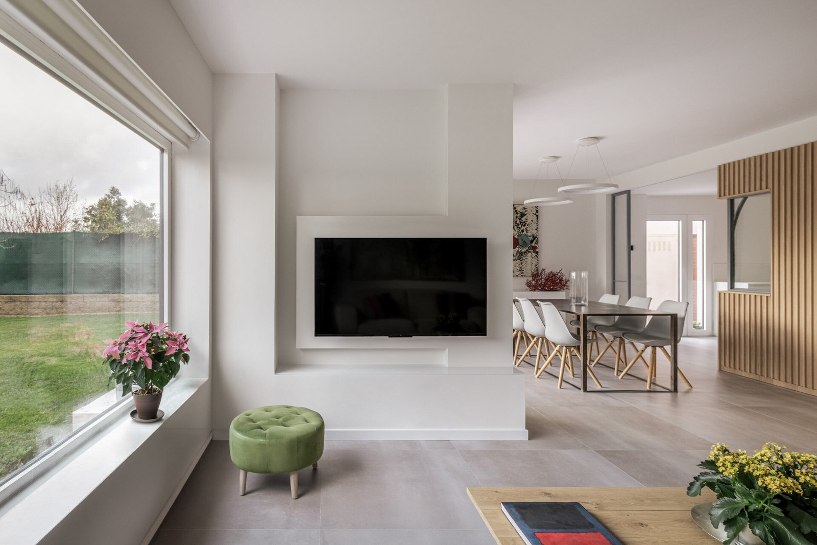 تشترك غرفة المعيشة في الجانب المواجه للحديقة من D + A House، مع تشطيبات بيضاء وأرضيات فاتحة وأبواب زجاجية منزلقة مخفية تساعد في الحفاظ على المخطط المفتوح.