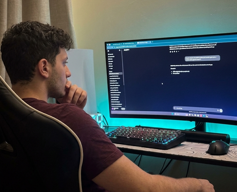 A naser bin ibrahim seated at a desk looking thoughtfully at a computer screen displaying a digital interface