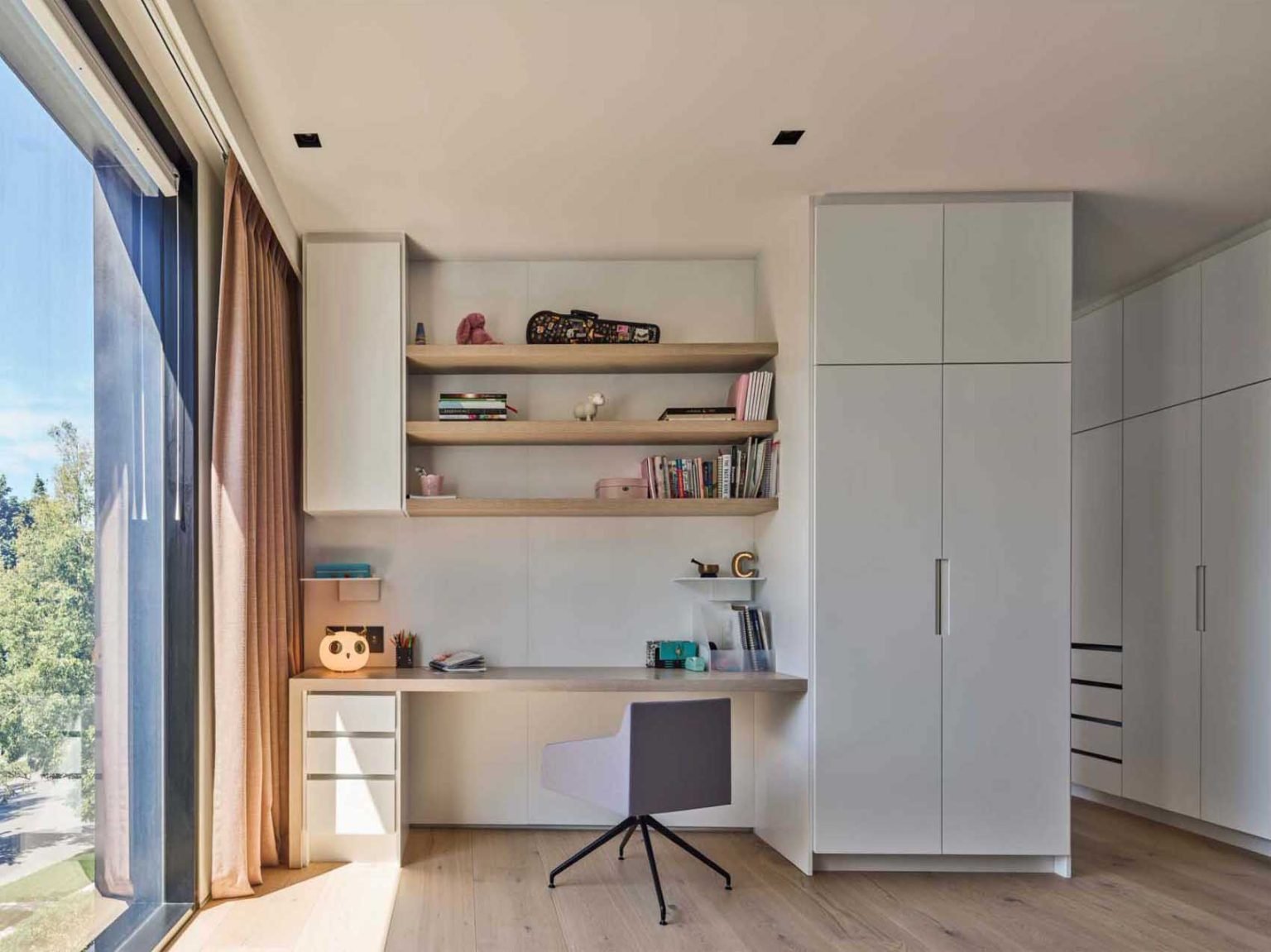 تحتوي غرفتي النوم في Nanton House على مكاتب مدمجة، مما يخلق مناطق مخصصة للدراسة ضمن التصميمات الداخلية الدافئة والمعاصرة لهذا المنزل متعدد الأجيال في فانكوفر.